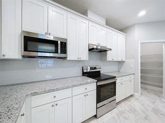 kitchen featuring marble finish floor, stainless steel appliances, white cabinetry, light stone countertops, and under cabinet range hood