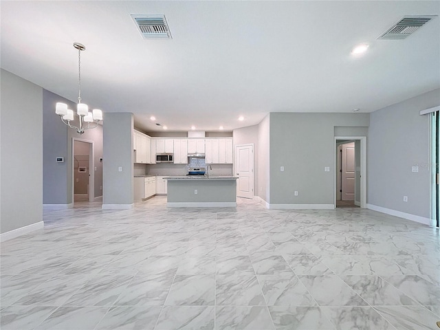 kitchen featuring open floor plan, visible vents, stainless steel microwave, and white cabinetry