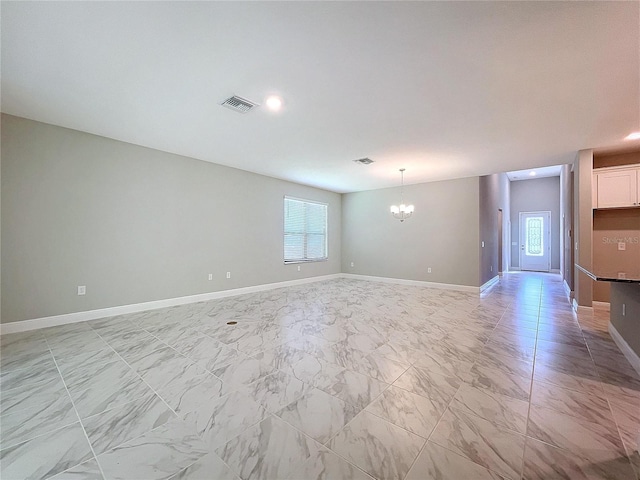 empty room featuring a healthy amount of sunlight, marble finish floor, visible vents, and a chandelier