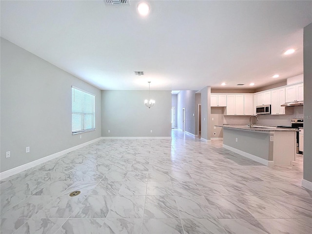 kitchen with marble finish floor, appliances with stainless steel finishes, open floor plan, white cabinets, and an island with sink