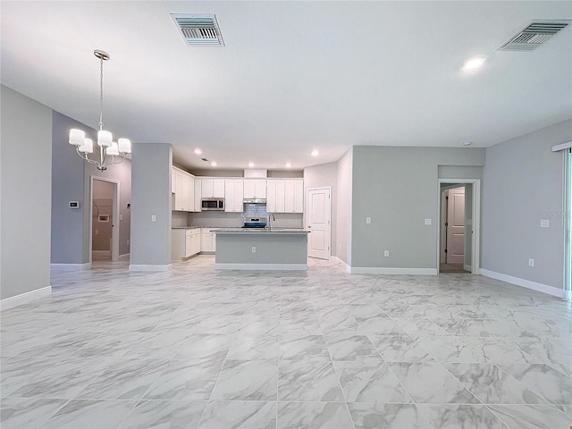 kitchen featuring white cabinets, visible vents, open floor plan, and stainless steel microwave