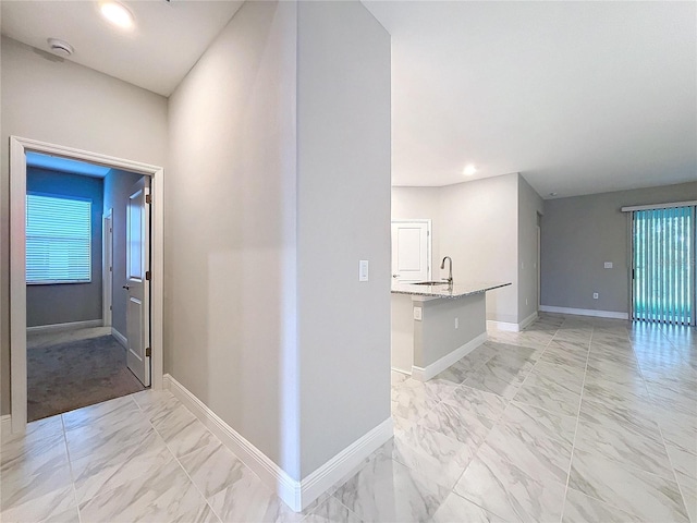 hall with marble finish floor, recessed lighting, a sink, and baseboards