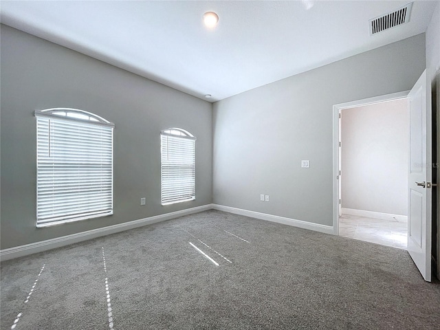 unfurnished room featuring baseboards, visible vents, and carpet flooring