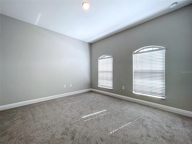 carpeted spare room featuring baseboards