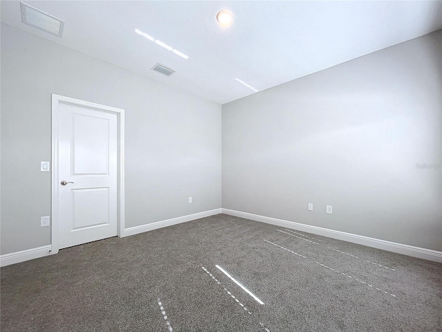 unfurnished room with dark colored carpet, visible vents, and baseboards