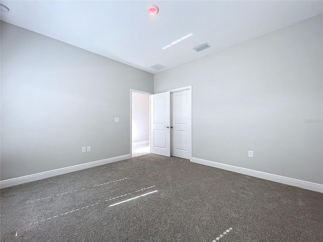 unfurnished bedroom with baseboards, visible vents, and dark carpet