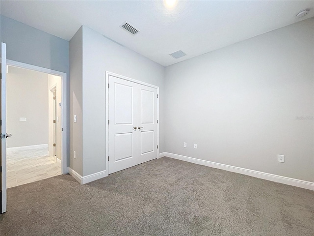 unfurnished bedroom with carpet, a closet, visible vents, and baseboards