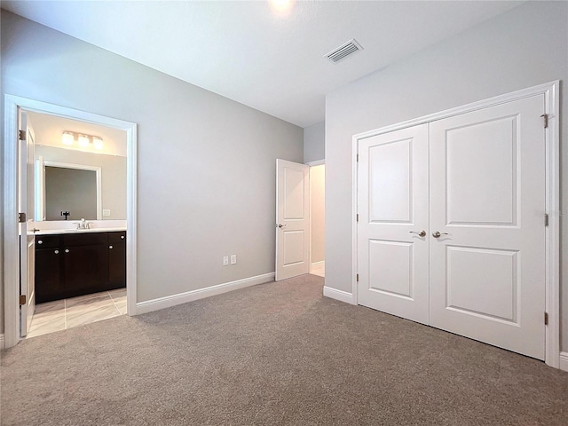 unfurnished bedroom featuring connected bathroom, light carpet, visible vents, baseboards, and a closet