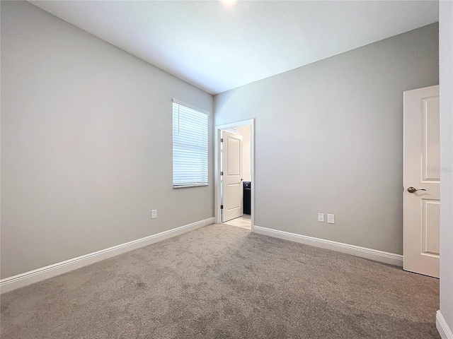 unfurnished room with baseboards and light colored carpet