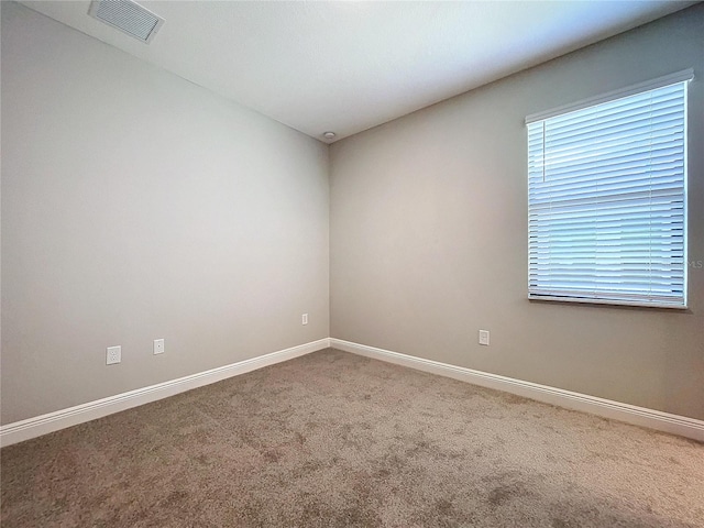 carpeted empty room featuring visible vents and baseboards