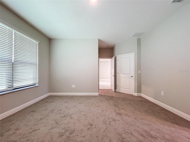 unfurnished room with carpet floors, visible vents, and baseboards