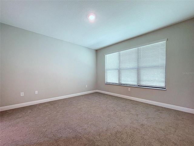 carpeted spare room featuring baseboards