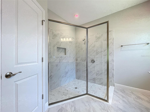 bathroom featuring marble finish floor, baseboards, and tiled shower