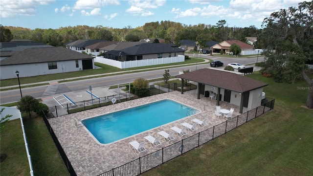 pool with a residential view, fence, a lawn, and a patio