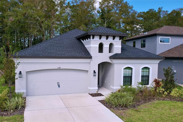 view of front of home featuring an attached garage, stucco siding, concrete driveway, and roof with shingles