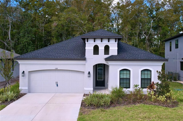 view of front facade featuring concrete driveway, a shingled roof, an attached garage, and stucco siding