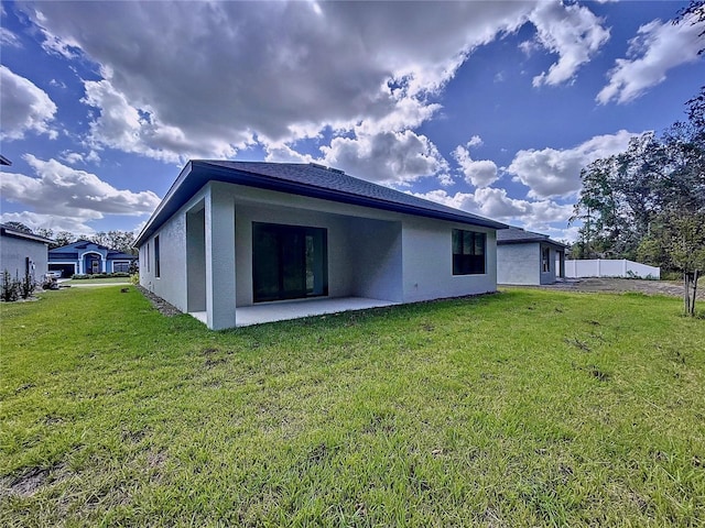 rear view of house featuring a patio area, stucco siding, and a yard