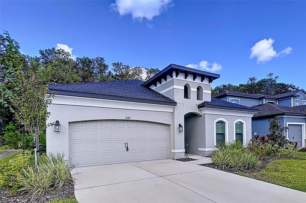 view of front of house with driveway, an attached garage, and stucco siding