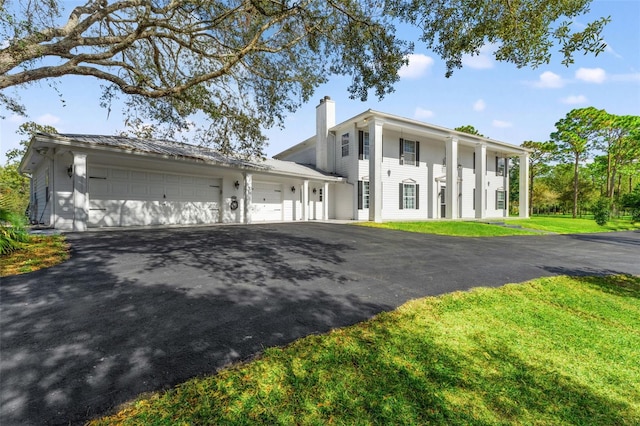 14485 Switch Back Rd, Brooksville, FL 34609 - neoclassical / greek revival house with a chimney, driveway, an attached garage, and a front yard
