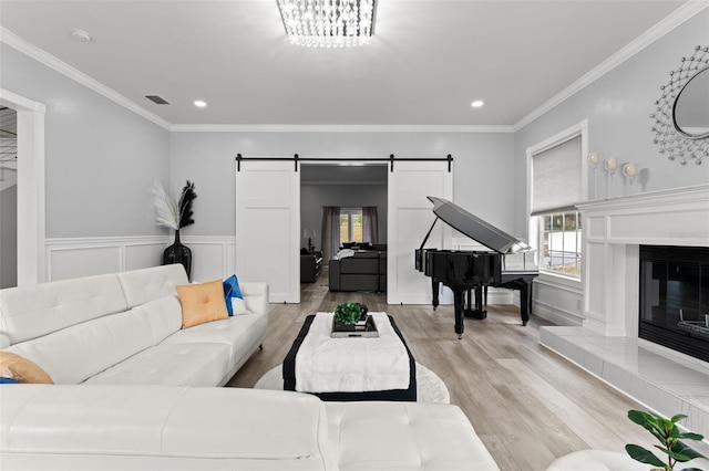 living room with a barn door, light hardwood / wood-style floors, and ornamental molding