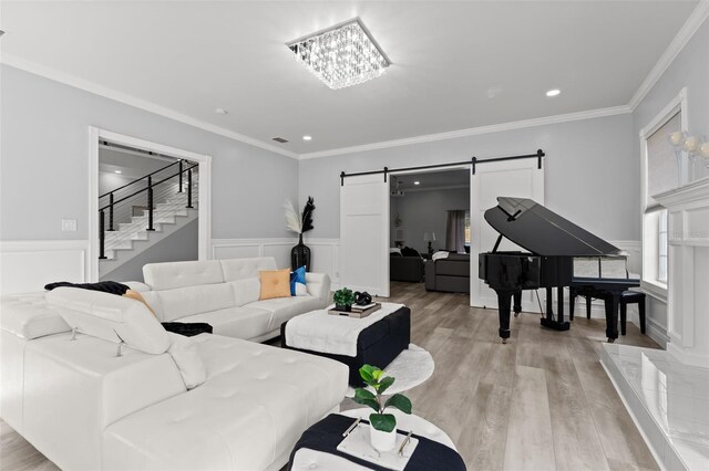 living room featuring a barn door, light hardwood / wood-style floors, and crown molding