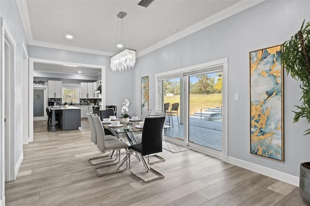 dining area with a notable chandelier, light hardwood / wood-style floors, and crown molding