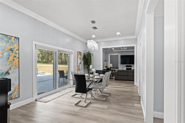 dining area with light hardwood / wood-style floors, an inviting chandelier, and ornamental molding