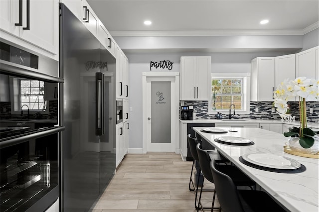 kitchen with white cabinets, stainless steel appliances, tasteful backsplash, and light stone countertops