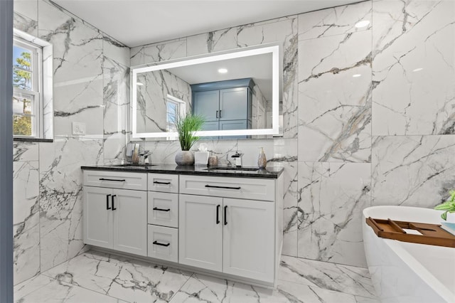 bathroom featuring a tub to relax in, vanity, and tile walls