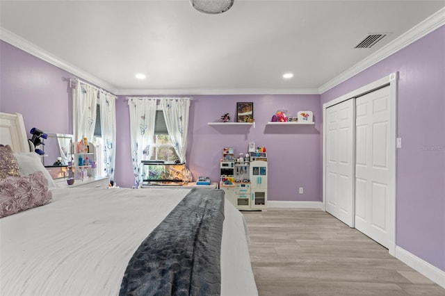 bedroom with ornamental molding, light wood-type flooring, and a closet