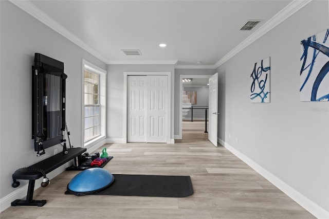 exercise room featuring ornamental molding and light hardwood / wood-style flooring