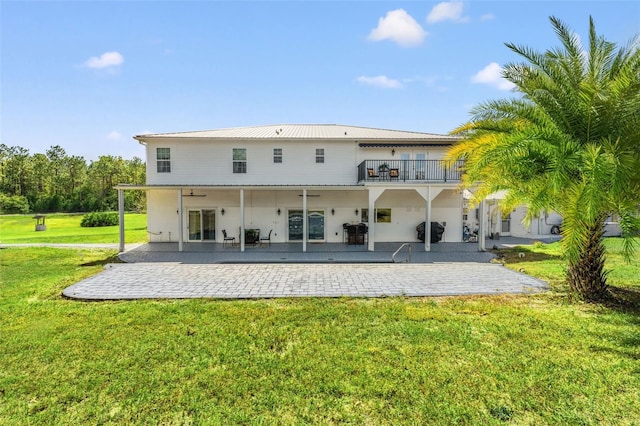 rear view of house featuring a balcony, a lawn, and a patio