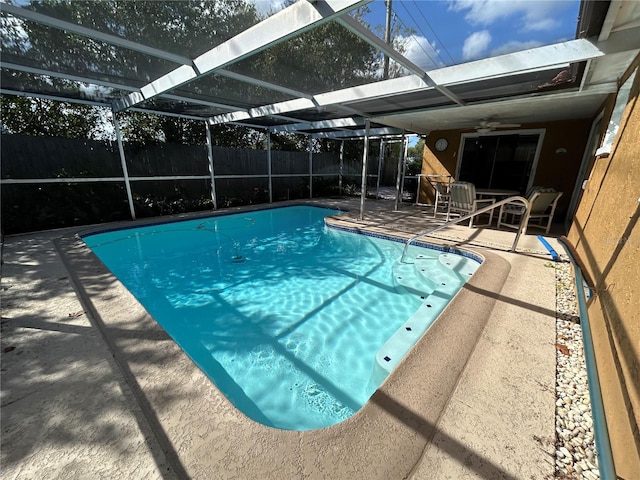 view of pool with glass enclosure, a patio, and ceiling fan