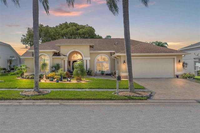 mediterranean / spanish-style home featuring a garage and a yard