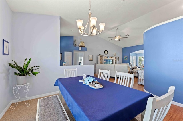 8231 Coral Creek Loop, Hudson, FL 34667 - dining area featuring arched walkways, a chandelier, a ceiling fan, vaulted ceiling, and baseboards