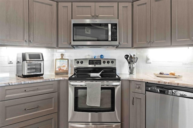 8231 Coral Creek Loop, Hudson, FL 34667 - kitchen featuring appliances with stainless steel finishes, gray cabinets, tasteful backsplash, and light stone countertops
