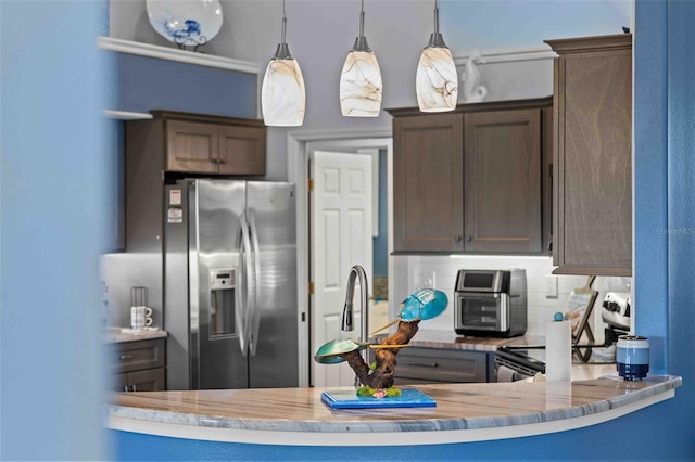 8231 Coral Creek Loop, Hudson, FL 34667 - kitchen with stainless steel fridge with ice dispenser, hanging light fixtures, backsplash, light stone counters, and a peninsula