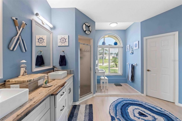 8231 Coral Creek Loop, Hudson, FL 34667 - bathroom featuring a stall shower, double vanity, wood finished floors, and baseboards