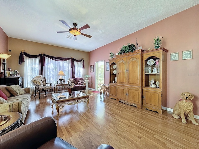 living room featuring a textured ceiling, light hardwood / wood-style flooring, and ceiling fan