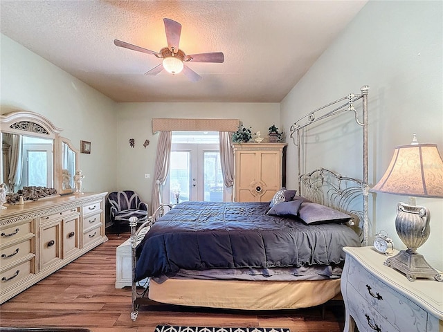 bedroom with access to outside, french doors, a textured ceiling, ceiling fan, and light hardwood / wood-style flooring