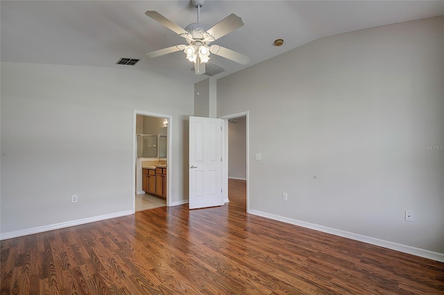 unfurnished bedroom featuring ensuite bath, ceiling fan, dark wood-type flooring, and vaulted ceiling