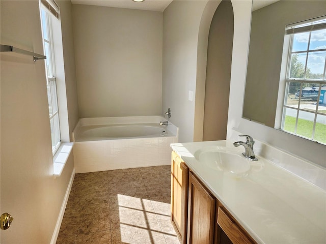 bathroom with tiled bath, tile patterned flooring, and vanity