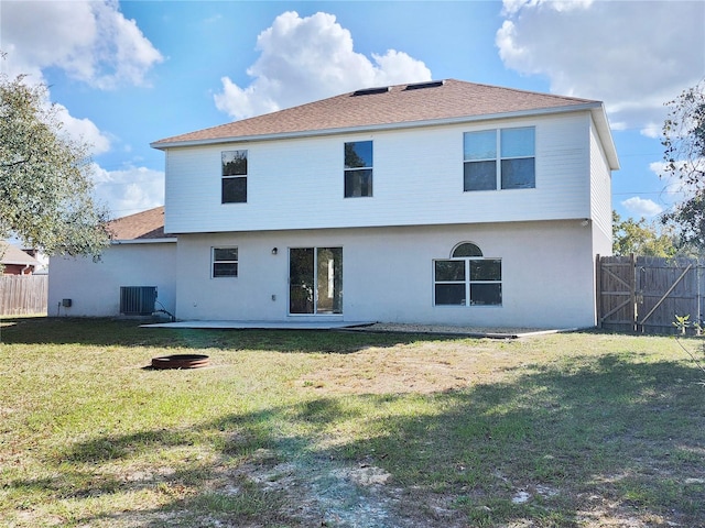 rear view of property with central AC and a yard