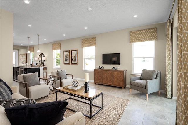 living room with a textured ceiling, light tile patterned floors, and sink