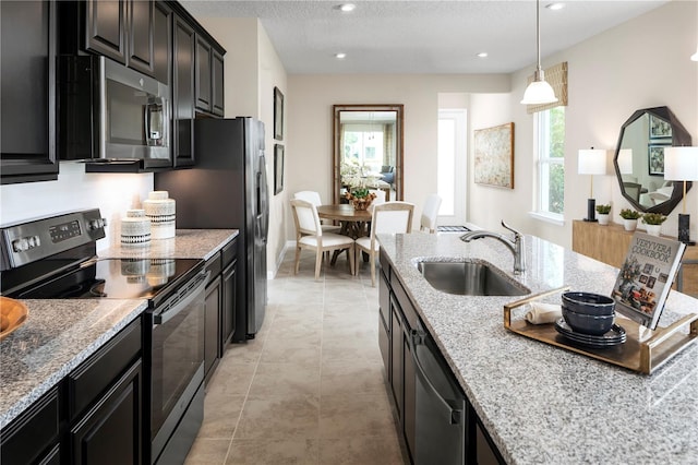 kitchen featuring light stone countertops, a healthy amount of sunlight, sink, and appliances with stainless steel finishes