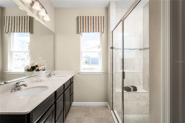 bathroom with tile patterned flooring, vanity, a textured ceiling, and a shower with door