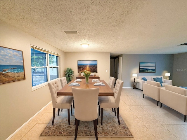 dining space featuring a textured ceiling and light tile patterned floors