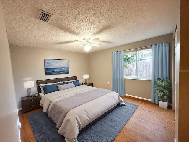 bedroom with a textured ceiling, hardwood / wood-style floors, and ceiling fan