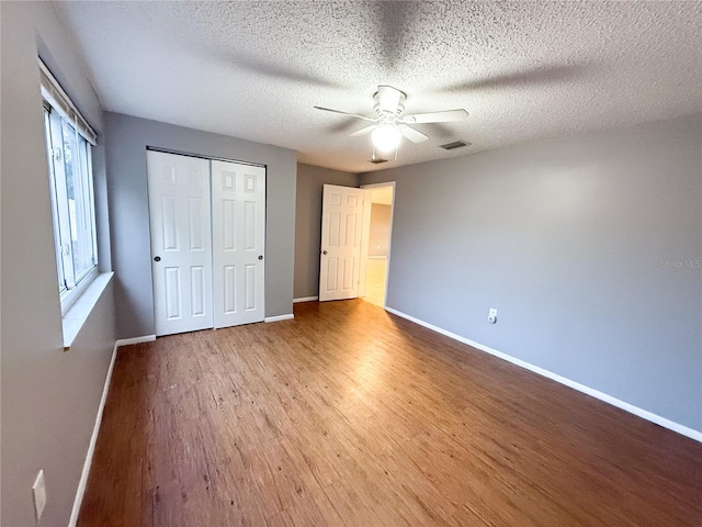 unfurnished bedroom featuring a closet, a textured ceiling, ceiling fan, and light hardwood / wood-style flooring