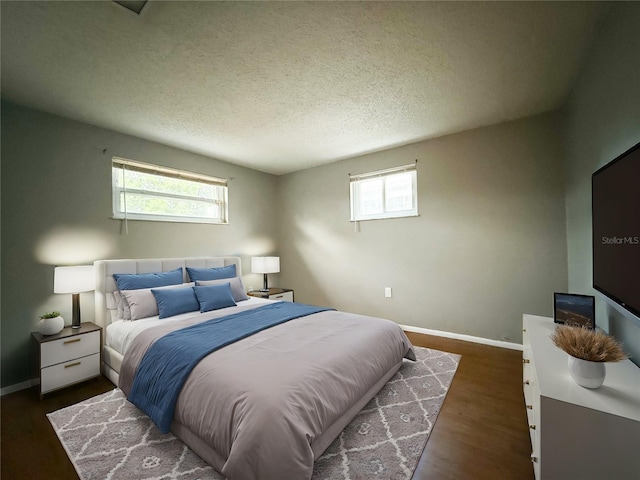 bedroom featuring dark wood-type flooring, multiple windows, and a textured ceiling